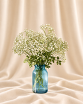 White gypsophila (baby's breath) + leafy greenery in a blue glass jar.